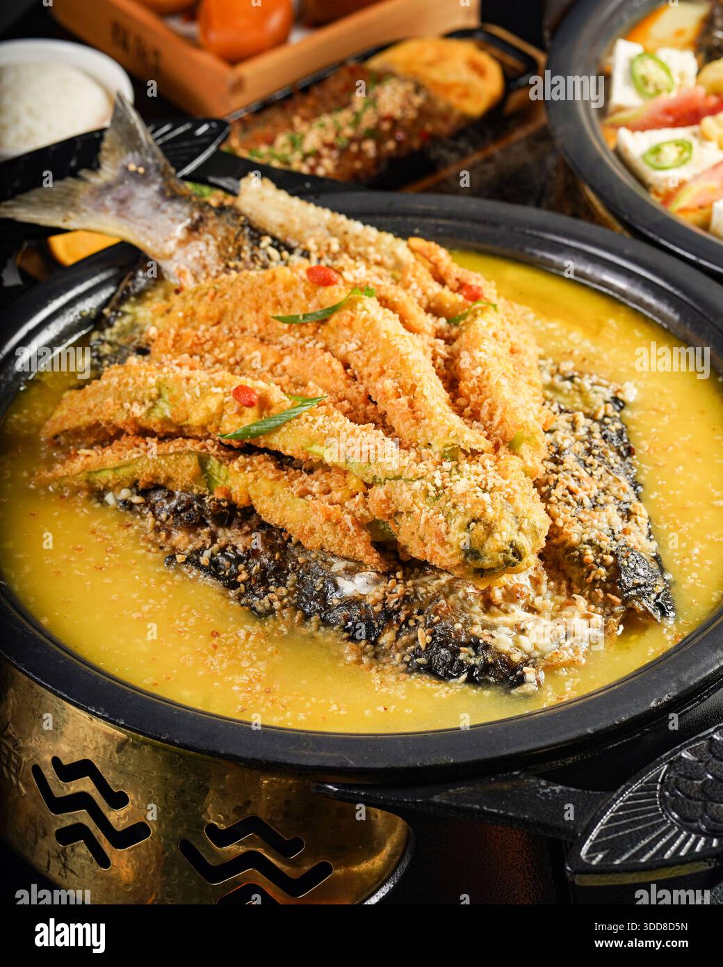 Schmackhaftes Fischgericht in einer Schüssel, garniert mit knusprigem Teig und Kräutern, serviert mit einer Seite herzhafter Sauce Stockfoto