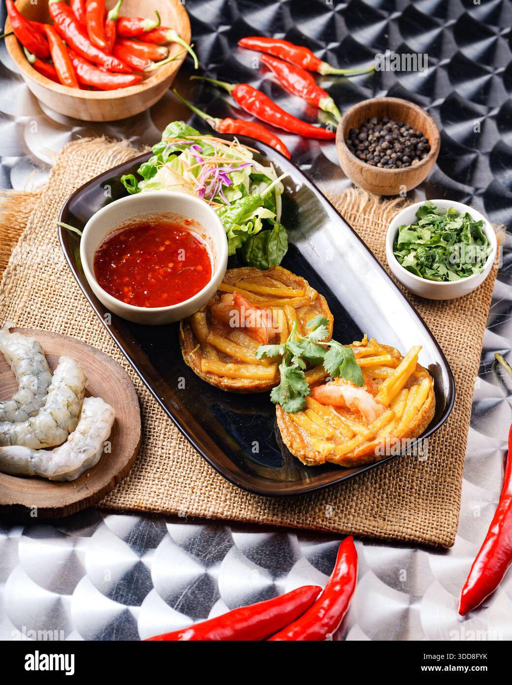 Leckeres vietnamesisches Gericht mit Garnelen, Pfannkuchen, Salat und scharfer Paprika auf einem rustikalen Tisch. Stockfoto