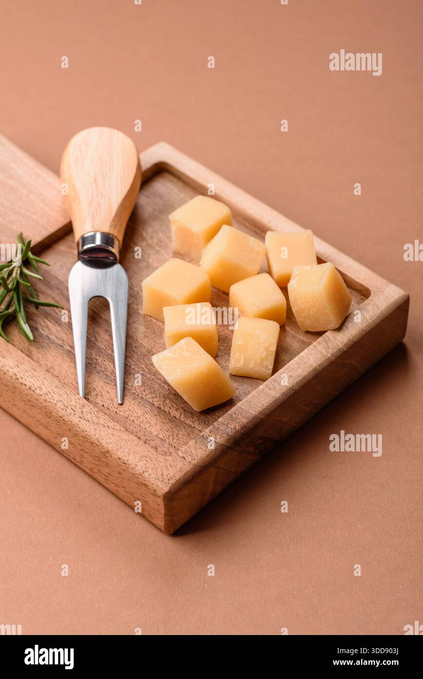 Gewürfelter Cheddar, Gouda oder Parmesankäse auf einem Schneidebrett. Gewürfelter Käse als Lebensmittelhintergrund für Ihr Design Stockfoto