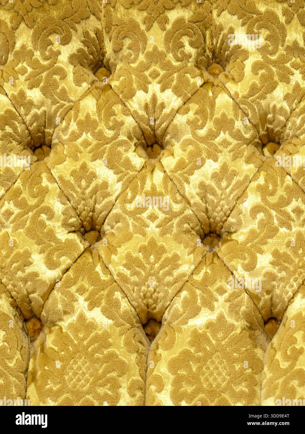 Veloursoberfläche der Close-up-Couch. Trainingsausrüstung - Velormatten mit Knöpfen festgezogen. Gelber chesterfield-Stil gesteppter Polsterhintergrund Nahaufnahme Stockfoto