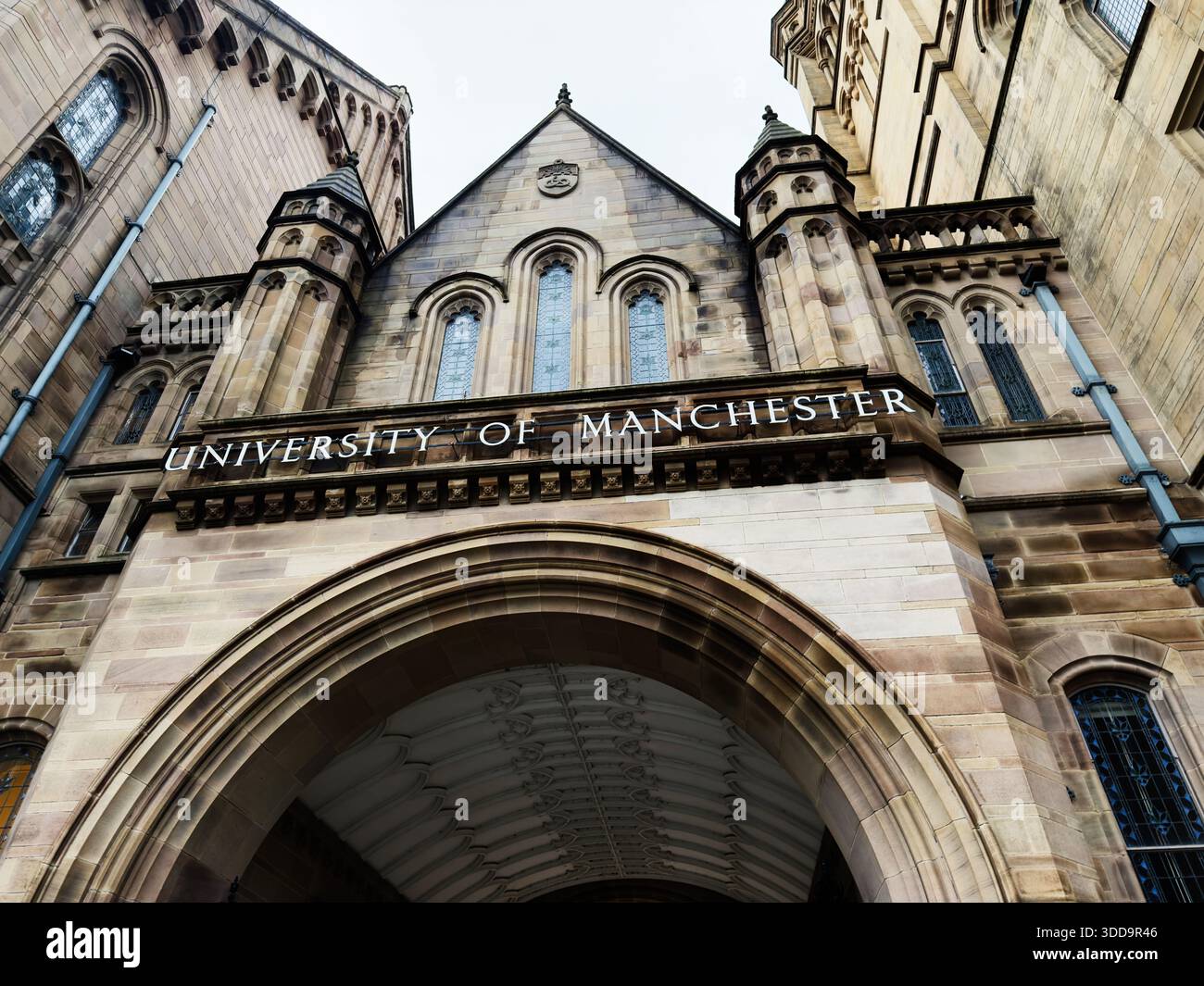 Manchester, Großbritannien - 06. Dezember 2025: Ein monumentaler Eingang zum Universitätsgebäude mit Bögen und Sandsteinfassade in Manchester, Großbritannien. Stockfoto