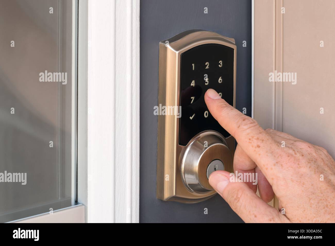Nahaufnahme einer Hand, die Tasten drückt, um einen Sicherheitscode auf der Tastatur für die Türverriegelung zu Hause einzugeben Stockfoto
