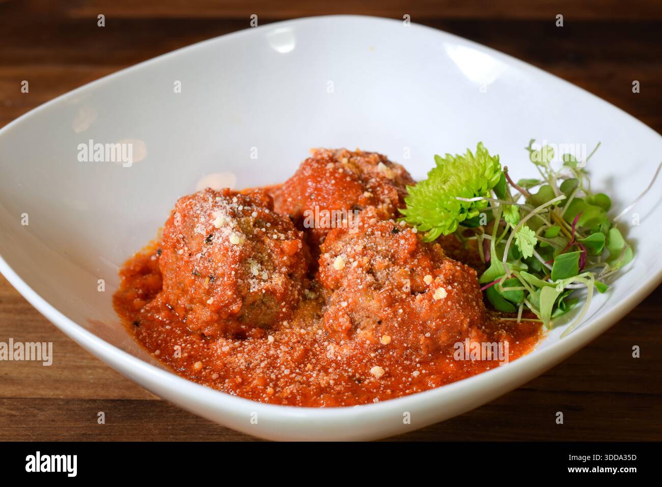 Fleischbällchen, serviert über Tomatensauce in einer weißen Schüssel, garniert mit gekeimtem Gemüse und Parmesankäse, serviert als herzhafte hausgemachte Mahlzeit Stockfoto