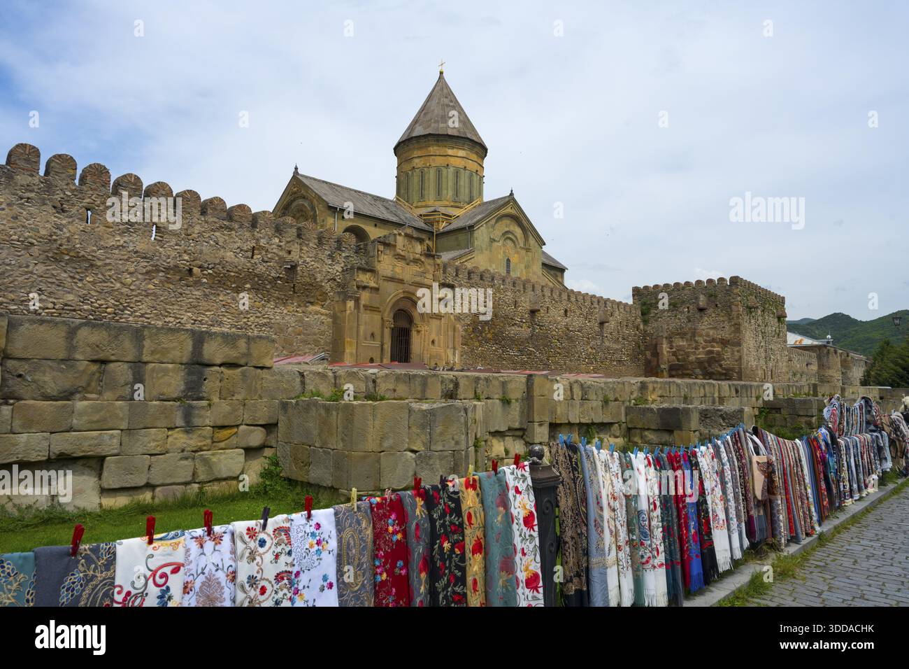 Steinfestung mit Kloster im Hintergrund, viele bunte Stoffe hängen davor, Svetitskhoveli Kathedrale, Svetitskhoveli, UNESCO Welt Stockfoto