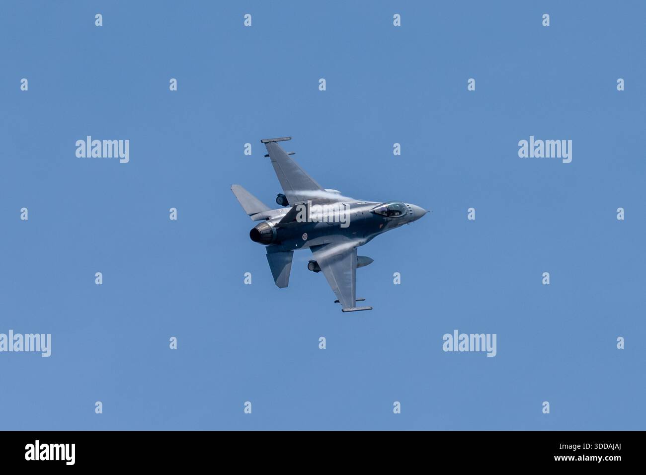 Beja, Portugal - 18. Juni 23: Ein militärischer F-16-Jet fliegt in einem klaren blauen Himmel und zeigt sein schlankes Design und Tarnmuster Stockfoto