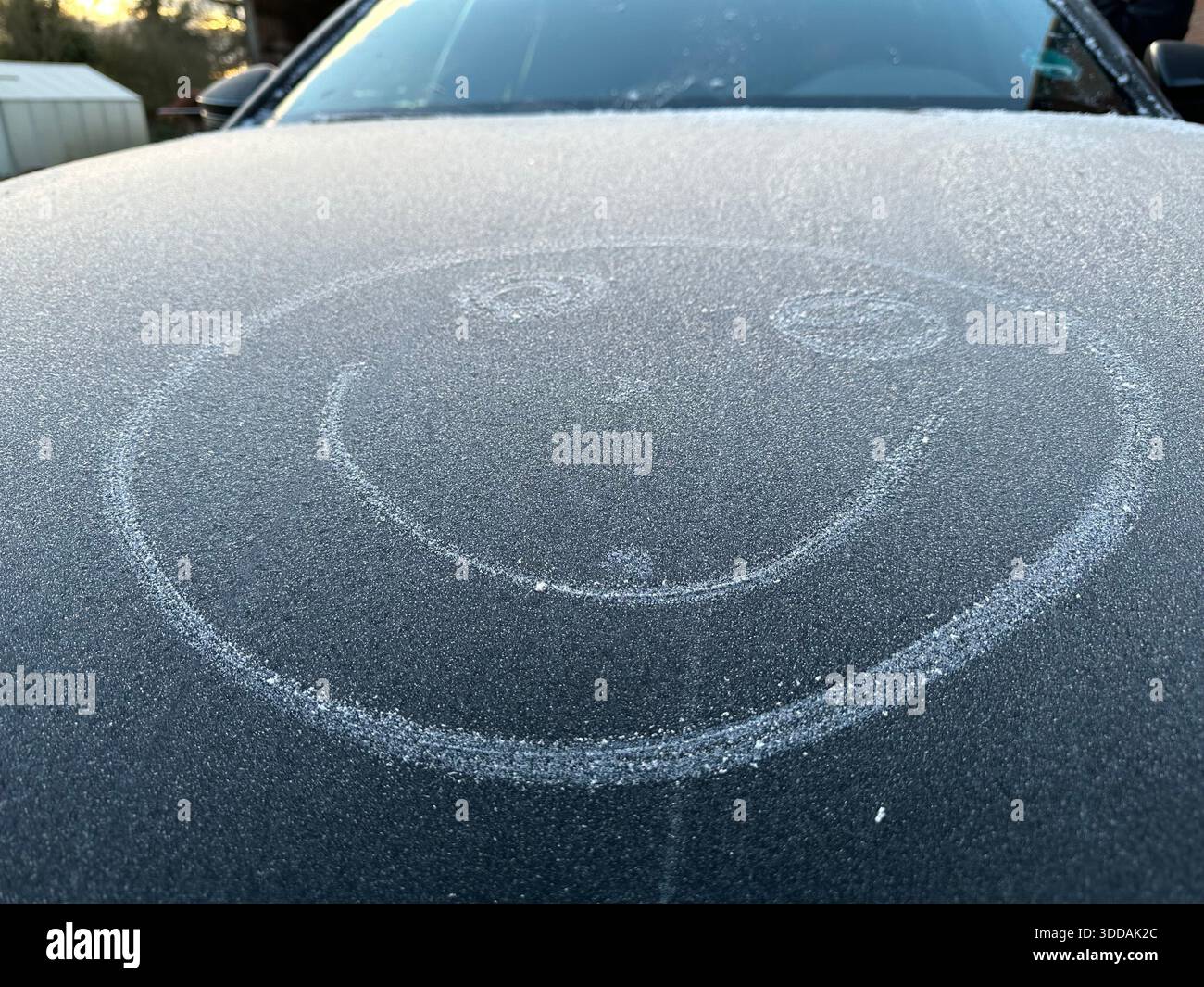 Ein lächelndes Gesicht, das an einem frostigen Tag auf einem Auto gemalt wurde - Smartphone-aufgenommenes Stockfoto