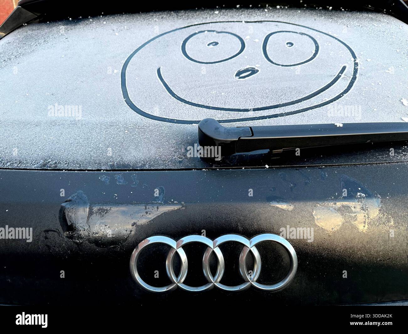 Ein lächelndes Gesicht auf einem Auto an einem frostigen Tag mit Audi Logo - Smartphone-aufgenommenes Stockfoto
