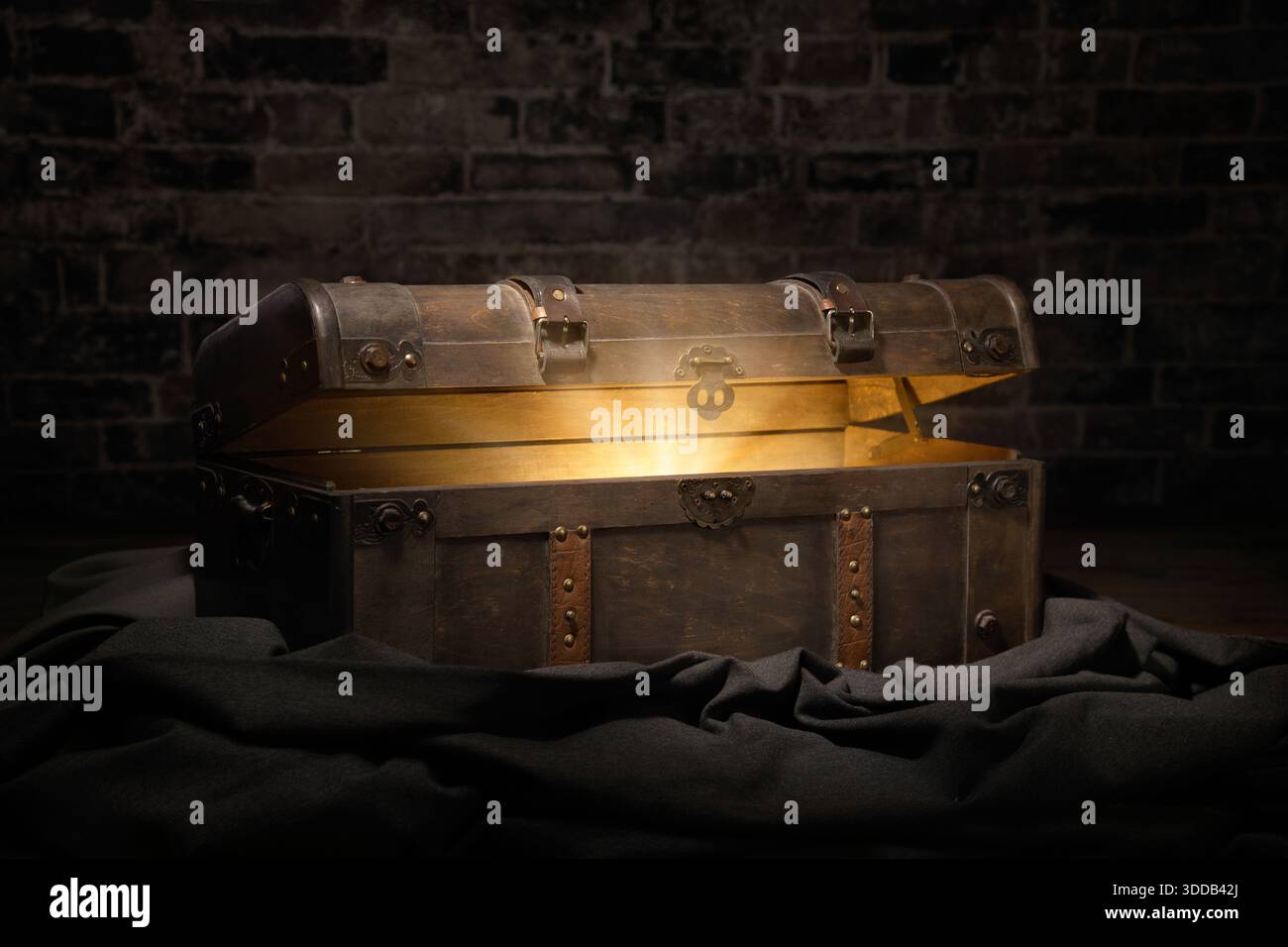Eine Vintage-Schatzkiste in einem dunklen Kerker öffnet sich, um ein leuchtendes, aber verborgenes Geheimnis zu enthüllen Stockfoto