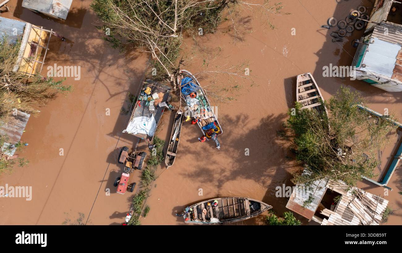 Aus der Vogelperspektive auf Boote im Hochwasser, die den Himmel reflektieren, Häuser unter Wasser und Bäume, die gegen die Strömung kämpfen, Beira, Provinz Sofala, Moz Stockfoto