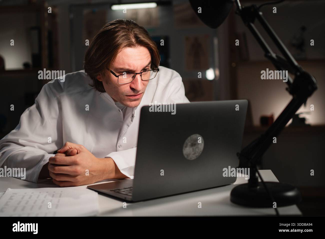 Junger Arzt, der während der Nachtschicht im Krankenhaus Brillen benutzt, während er mit Sehstörungen arbeitet. Sehstörungen. Kopierbereich Stockfoto