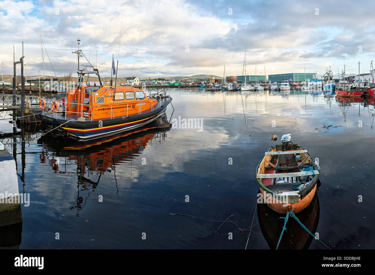 RNLI-Rettungsboot und kleines Fischereischiff liegen im Hafen von Arklow und spiegeln das maritime Erbe und den Sicherheitsschwerpunkt der Stadt wider. Stockfoto