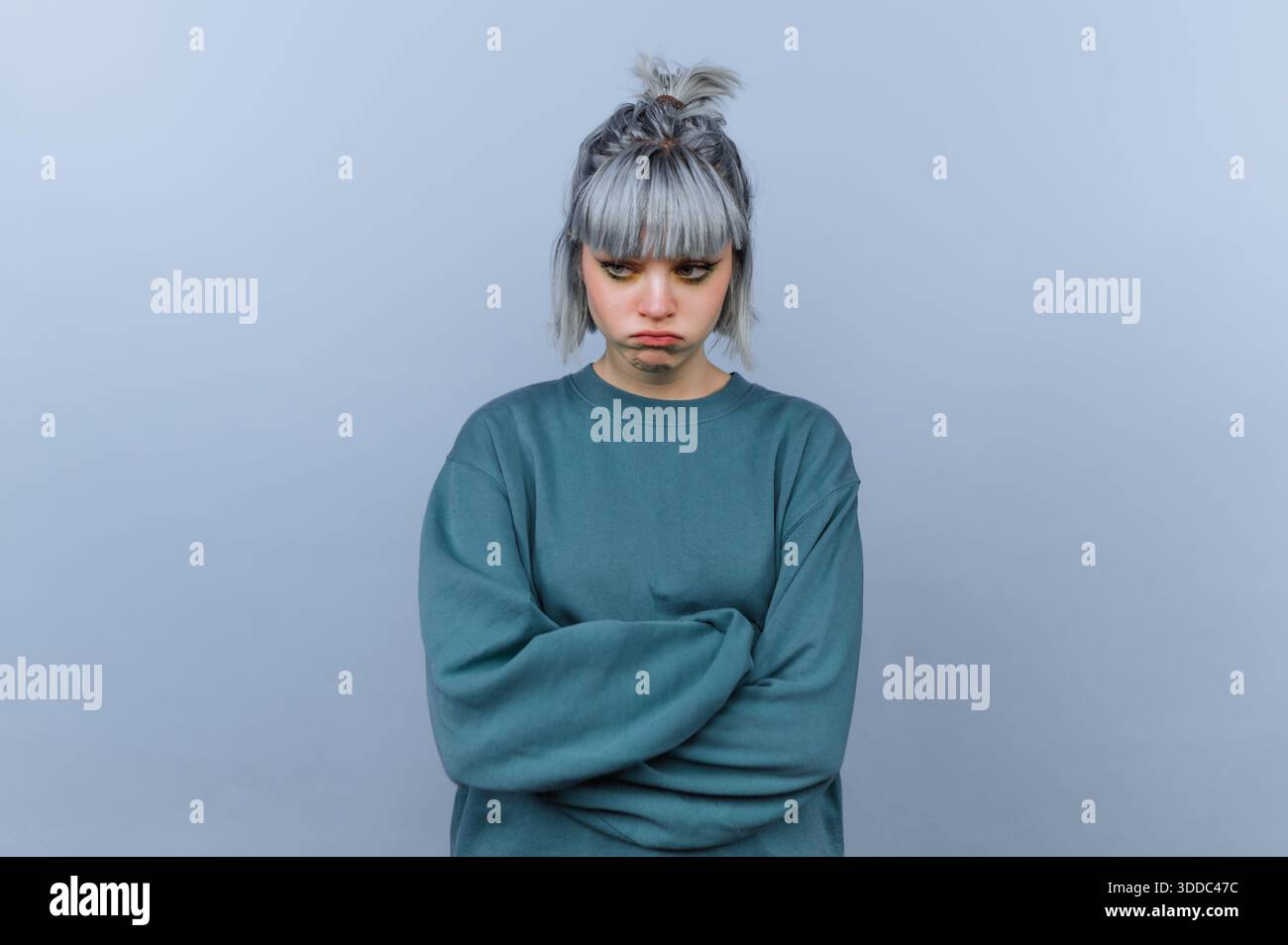 Eine junge Frau mit grauem Haar in einem blauen Pullover, der traurig aussieht. Stockfoto