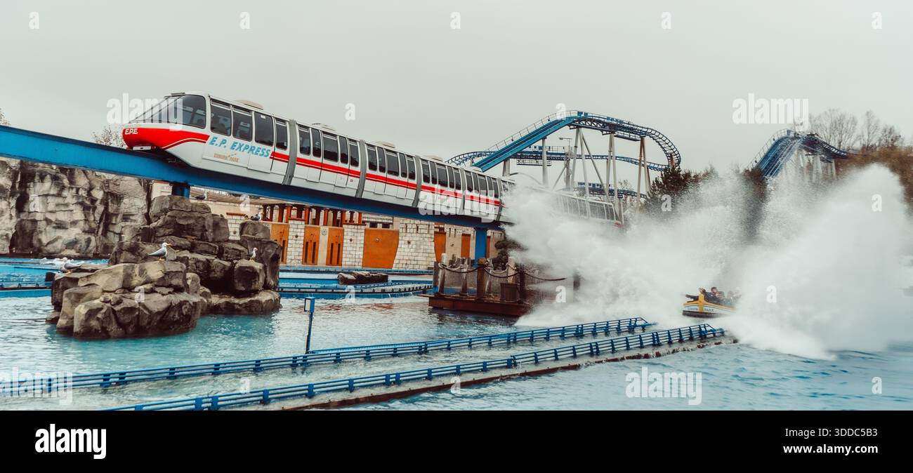Die Monorail fährt an der Wasserachterbahn Poseidon im Europa-Park in Rust, Deutschland, vorbei, mit einem Spritzer Wasser im Hintergrund Stockfoto