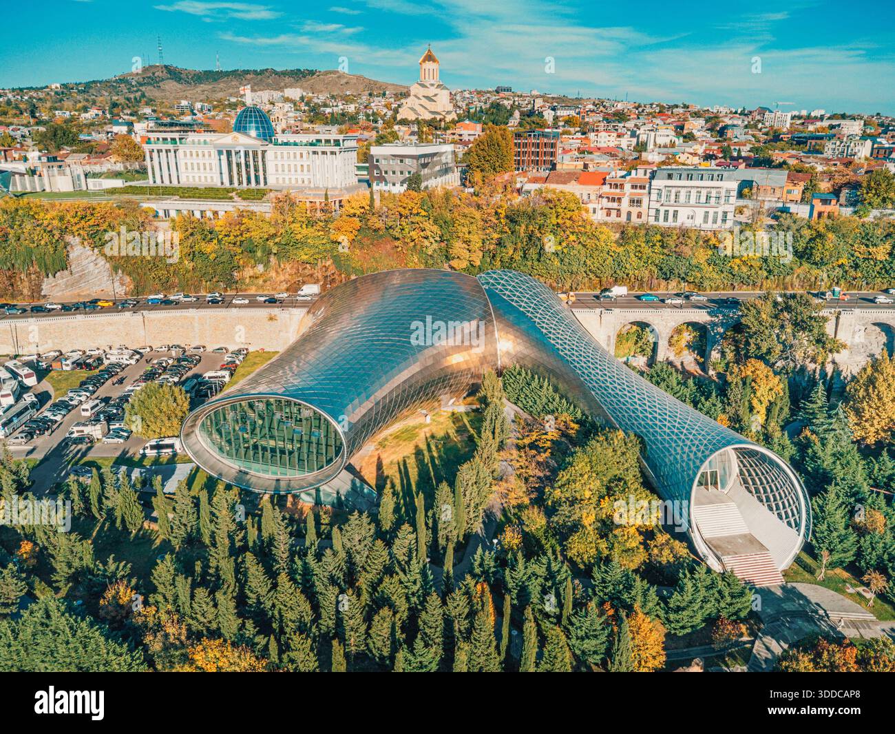 31. Oktober 2025, Tiflis, Georgien: Rike Park Konzerthalle mit Präsidentenpalast und Sameba Kathedrale im Hintergrund an einem Herbsttag Stockfoto