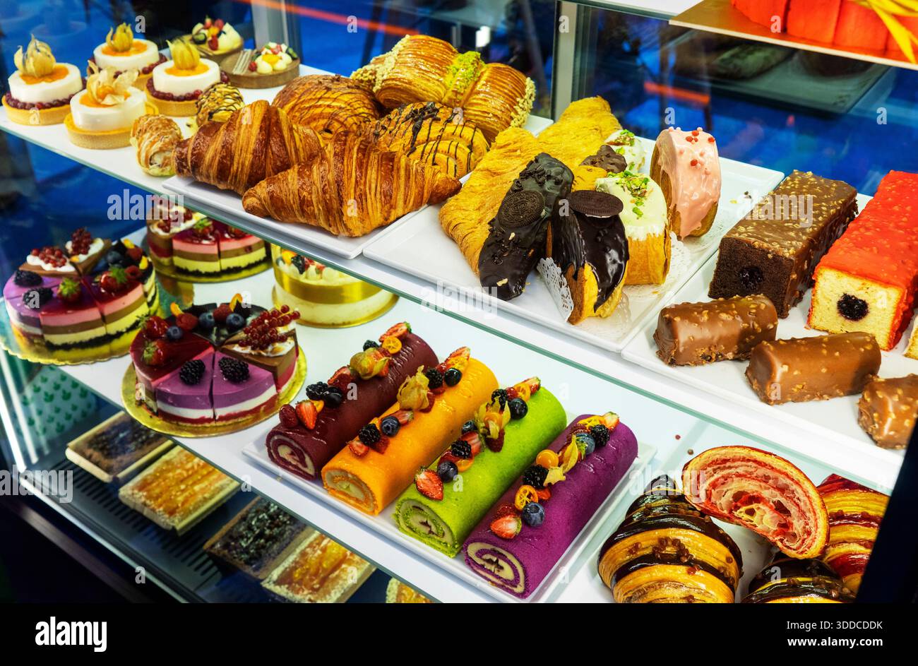 Verschiedene Kuchen mit Sahne und verschiedene Früchte in den Regalen des Ladens Stockfoto