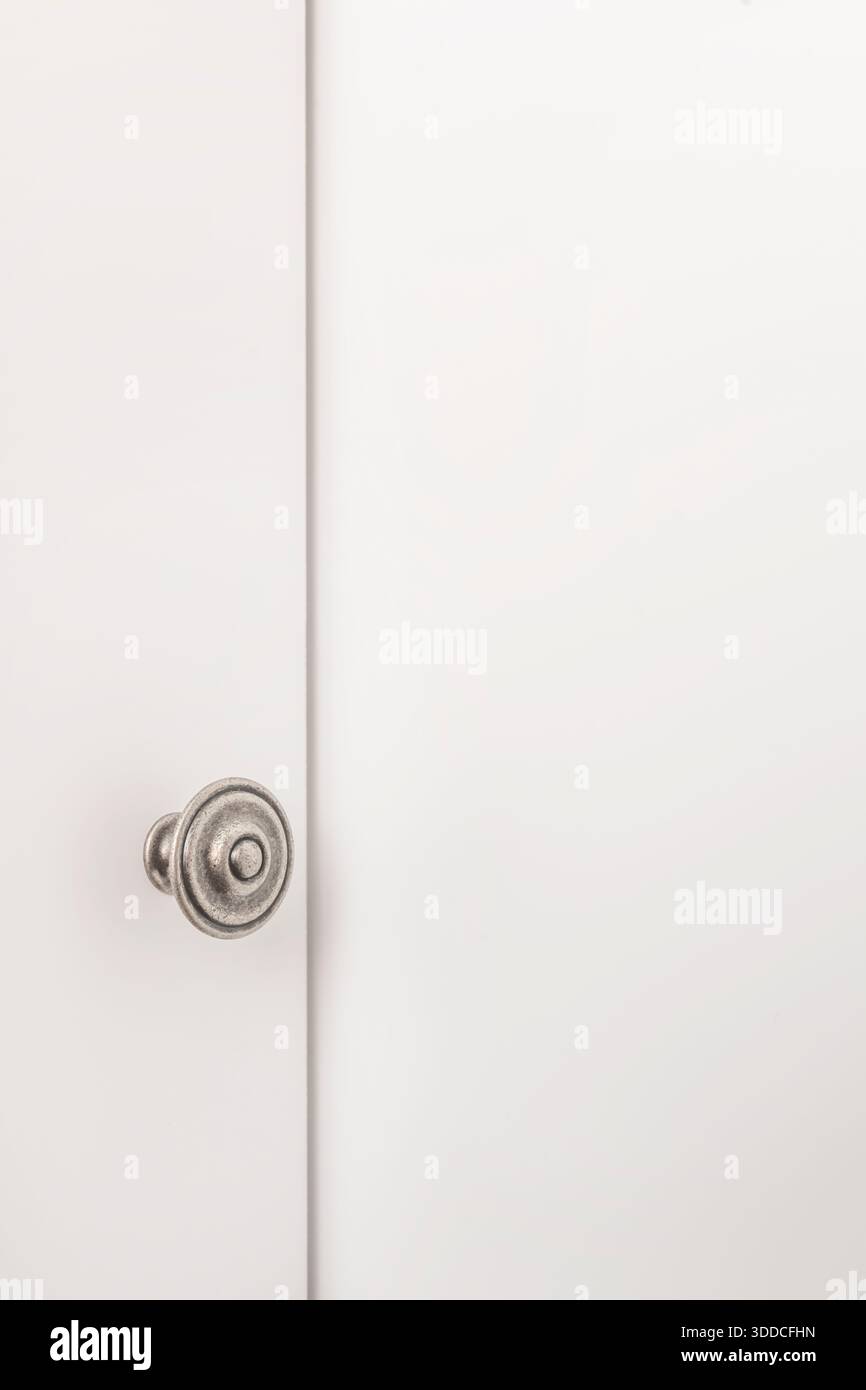 Die Nahaufnahme konzentriert sich auf einen schlanken, glänzenden, runden silbernen Metallgriff, der in der Mitte einer dunkelgrauen Melamin-Garderobentür angebracht ist und ein stilvolles A schafft Stockfoto