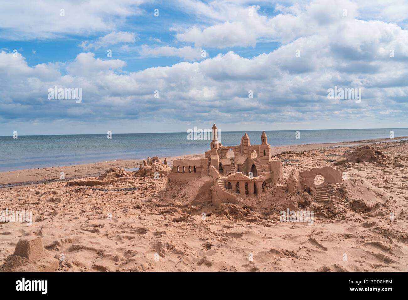 Eine Sandburg am Strand mit dem Meer im Hintergrund. Stockfoto