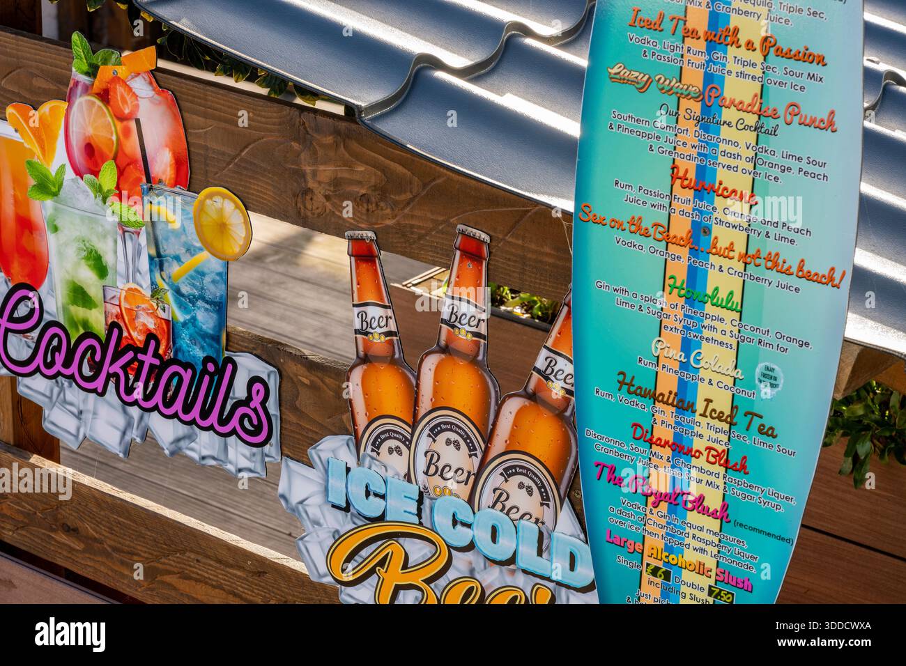 Menü und Preisliste in einem Strandcafé, gedruckt auf einem alten Surfbrett mit bunten Bildern von Bieren und Cocktails. Stockfoto