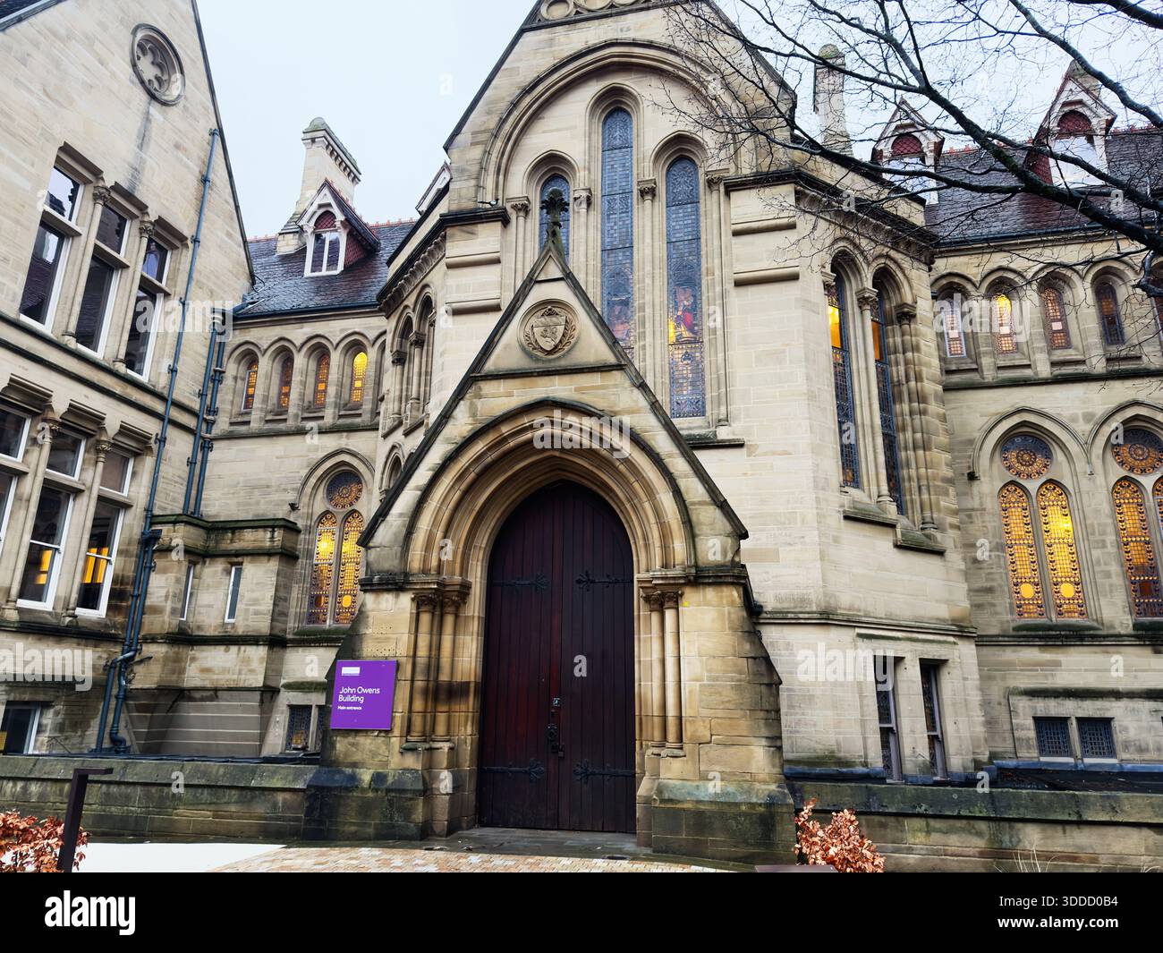 Manchester, Großbritannien - 06. Dezember 2025: Das gotische John Owens Campus-Gebäude in Manchester verfügt über eine bogenförmige Eingangstür, Buntglas und eine warme Inneneinrichtung Stockfoto