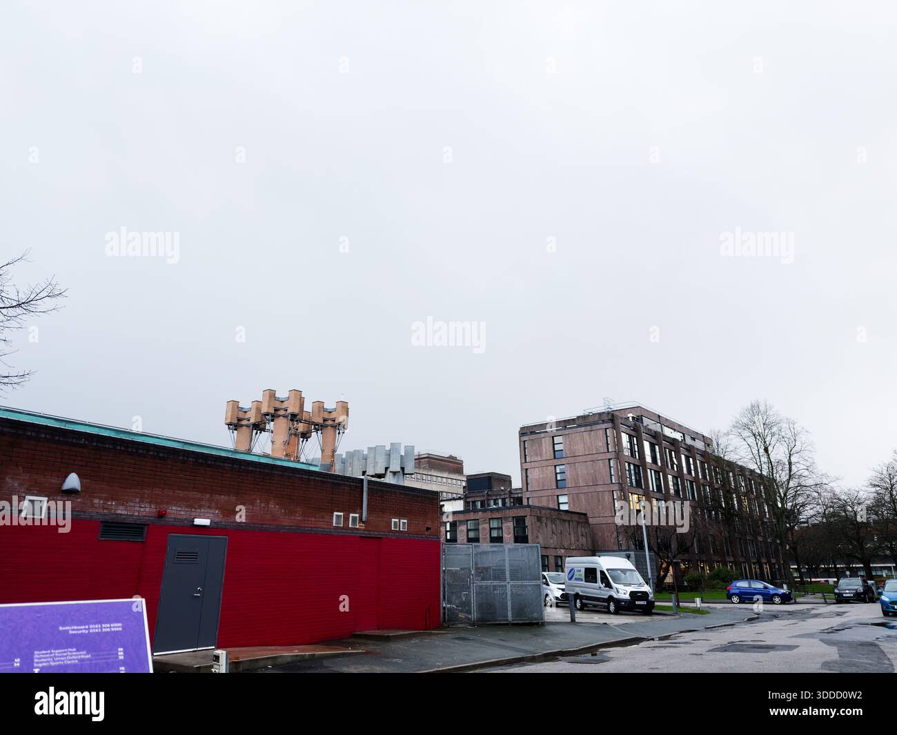 Manchester, Großbritannien - 06. Dezember 2025: Bewölktes Stadtbild in Manchester mit Industriemauern, Minibus und ruhiger urbaner Umgebung. Stockfoto