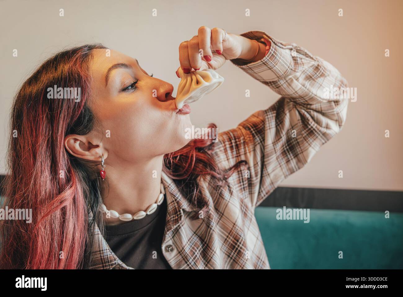Junge Frau, die ein großes Khinkali-Knödel genießt und authentische georgische Küche in einem Restaurant genießt Stockfoto