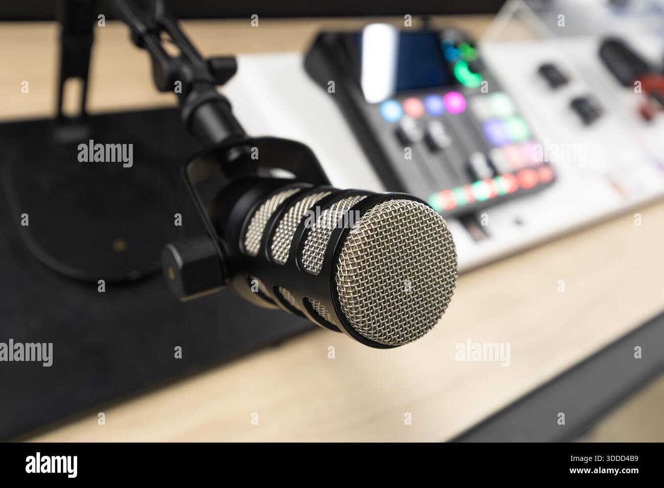 Arbeitsbereich für Podcast-Aufnahmen mit professionellem Kondensatormikrofon auf verstellbarem Ständer und digitalem Audio-Mixer mit beleuchteten Bedienelementen auf einem modernen D Stockfoto