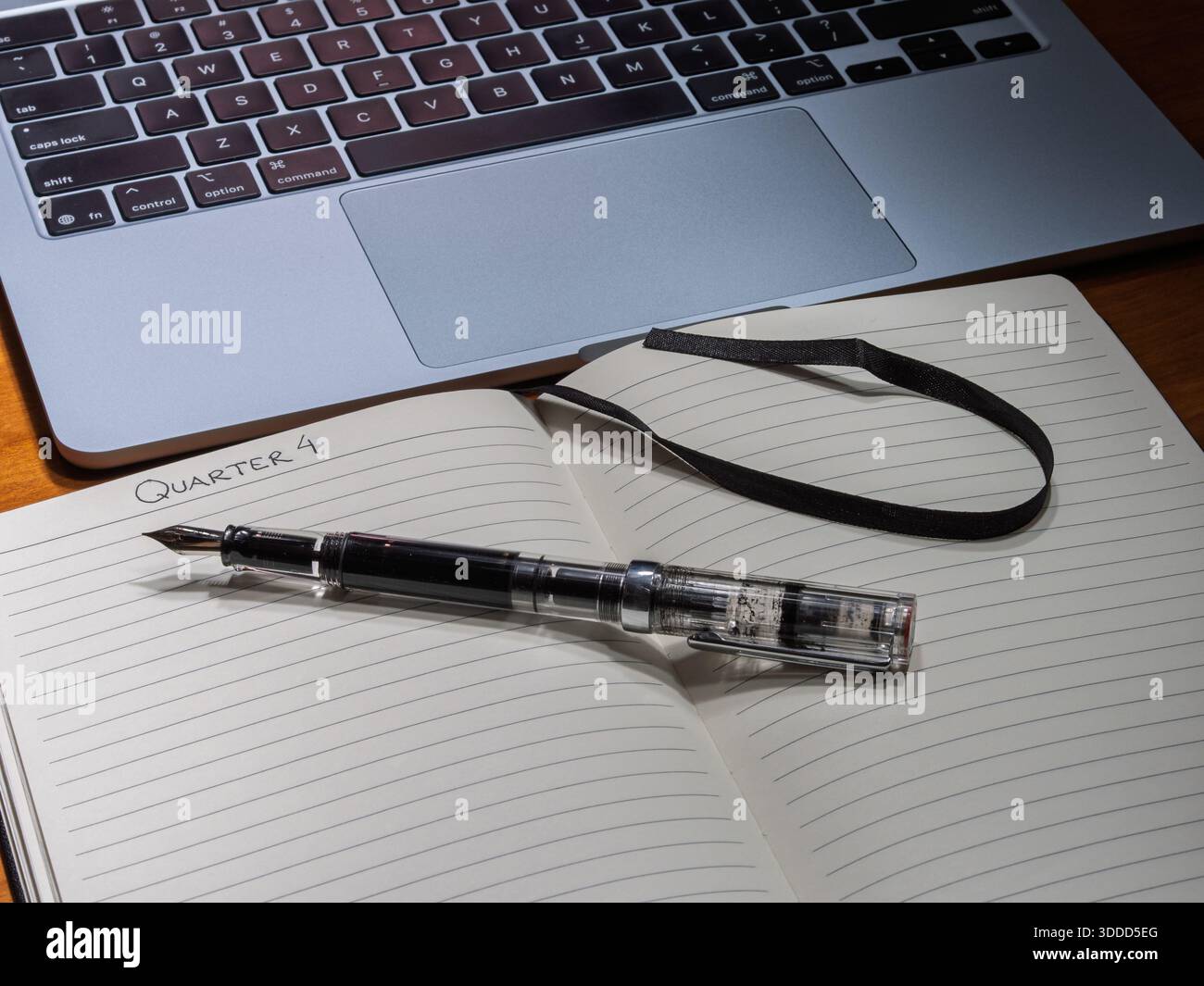 Strategische Planung für das vierte Quartal mit einem Füllfederhalter und einem Kugeljournal auf einem Schreibtisch, die einen hybriden analogen und digitalen Workflow veranschaulichen. Stockfoto