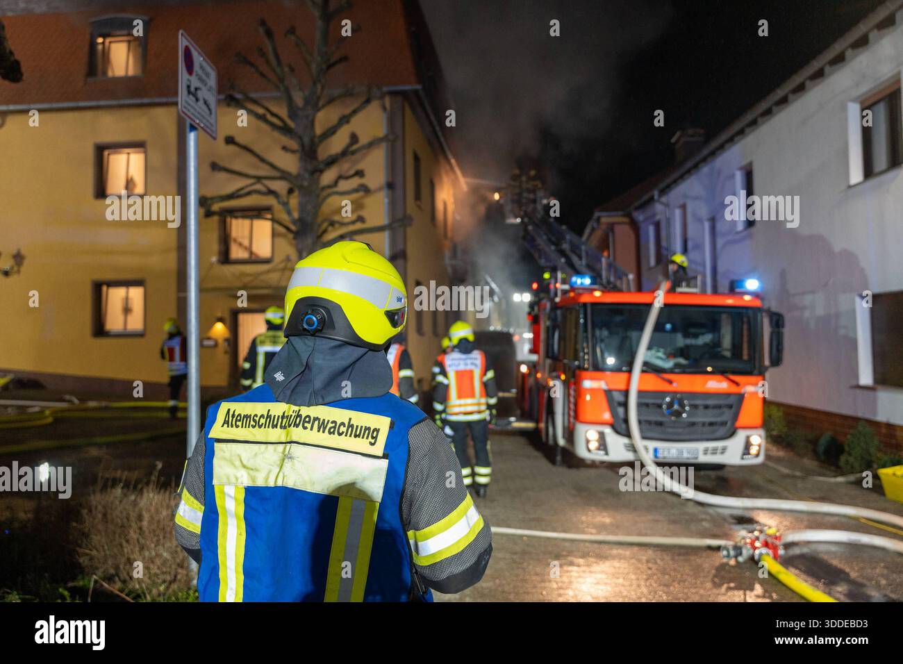 Lieferwagen brennt neben Gebäude Feuer greift auf Dachstuhl über am 31.12.2025 geriet kurz vor 02:00 Uhr ein Lieferwagen in Brand, der direkt neben einem Gebäude mit Wohn- und Geschäftseinheiten in Bickenbach Stand. Die Flammen griffen auf den angrenzenden Dachstuhl über und breiteten sich auf dem Großteil des Dachbodens aus. Da dieser nicht von innen erreichbar war, müssen die Einsatzkräfte die gesamten Dachziegel entfernen, um gezielte Löschmaßnahmen durchführen zu können. Vier Drehleitern sowie ein Mast der Werkfeuerwehr Merck kam zum Einsatz. Winterliche Minusgrade erschwerten die Lösc Stockfoto