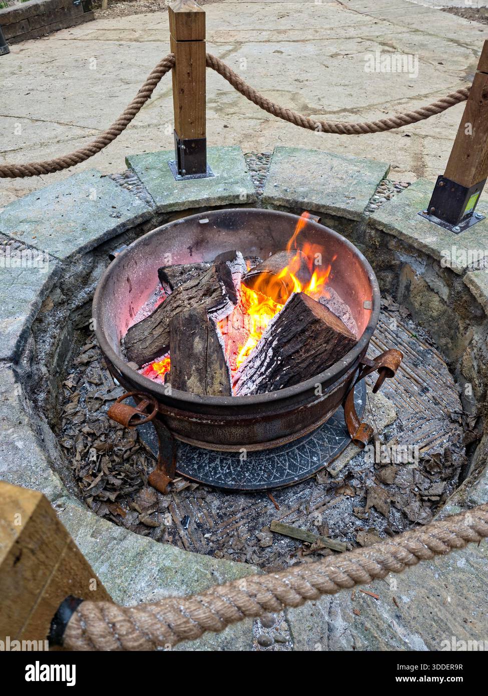 Feuerstelle im Freien mit brennenden Stämmen in Stone Surround, England Stockfoto
