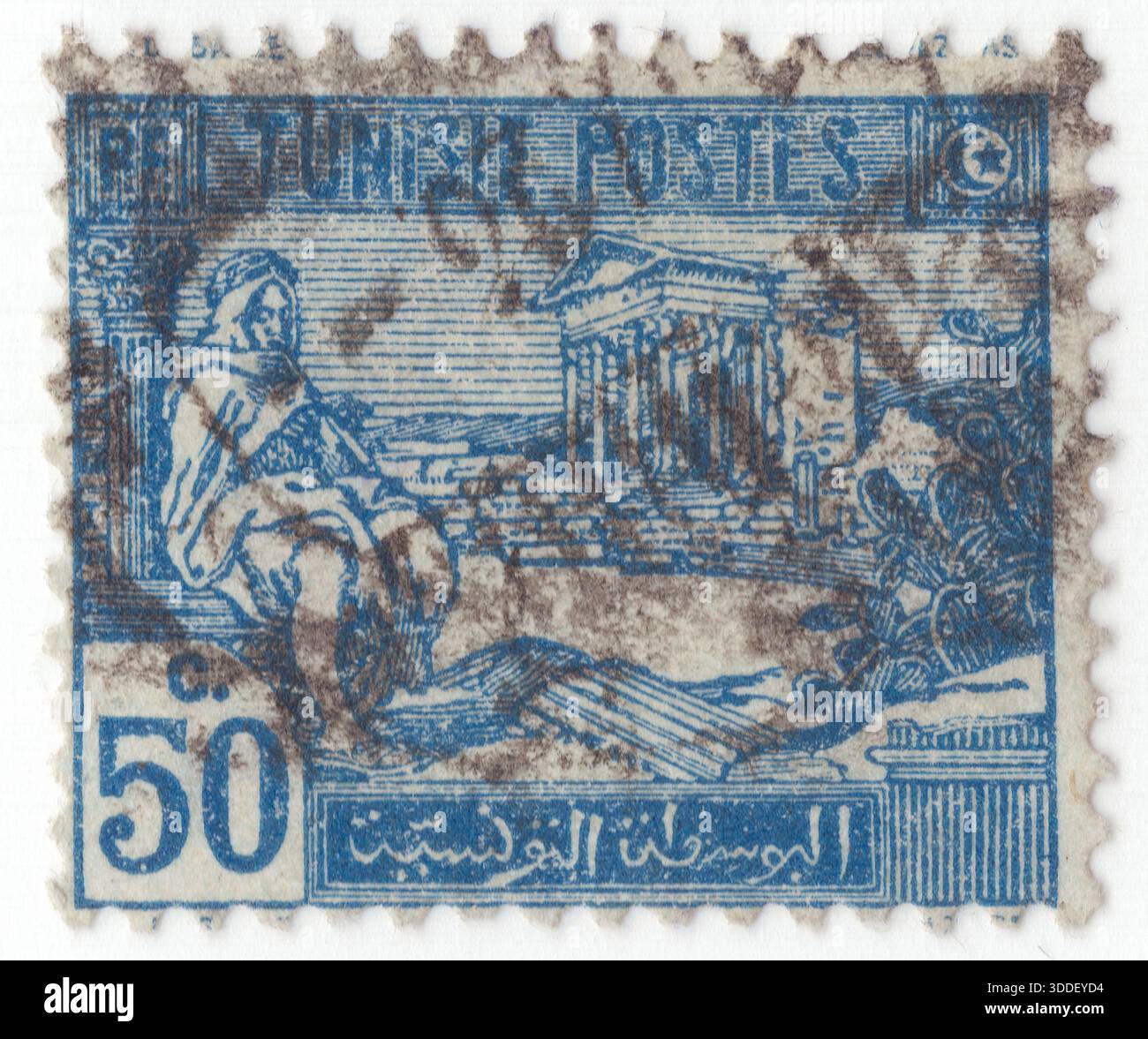 TUNESIEN - 1922: 50 Centime blaue Briefmarke mit Darstellung der arabischen Ureinwohner und Ruinen von Dougga. Thugga oder TBGG war eine antike Siedlung in der Nähe des heutigen Téboursouk im Norden Tunesiens. Der Kapitolinische Tempel gilt weithin als der prächtigste und am besten erhaltene römische Tempel in Nordafrika. Es befindet sich im Herzen der archäologischen Stätte im Nordwesten Tunesiens und ist ein UNESCO-Weltkulturerbe, das seit fast 2.000 Jahren steht. Das Capitol ist das Kronjuwel von Dougga, einer Stadt, die auf einzigartige Weise numidische (Berber), Punische und römische Einflüsse verbindet Stockfoto