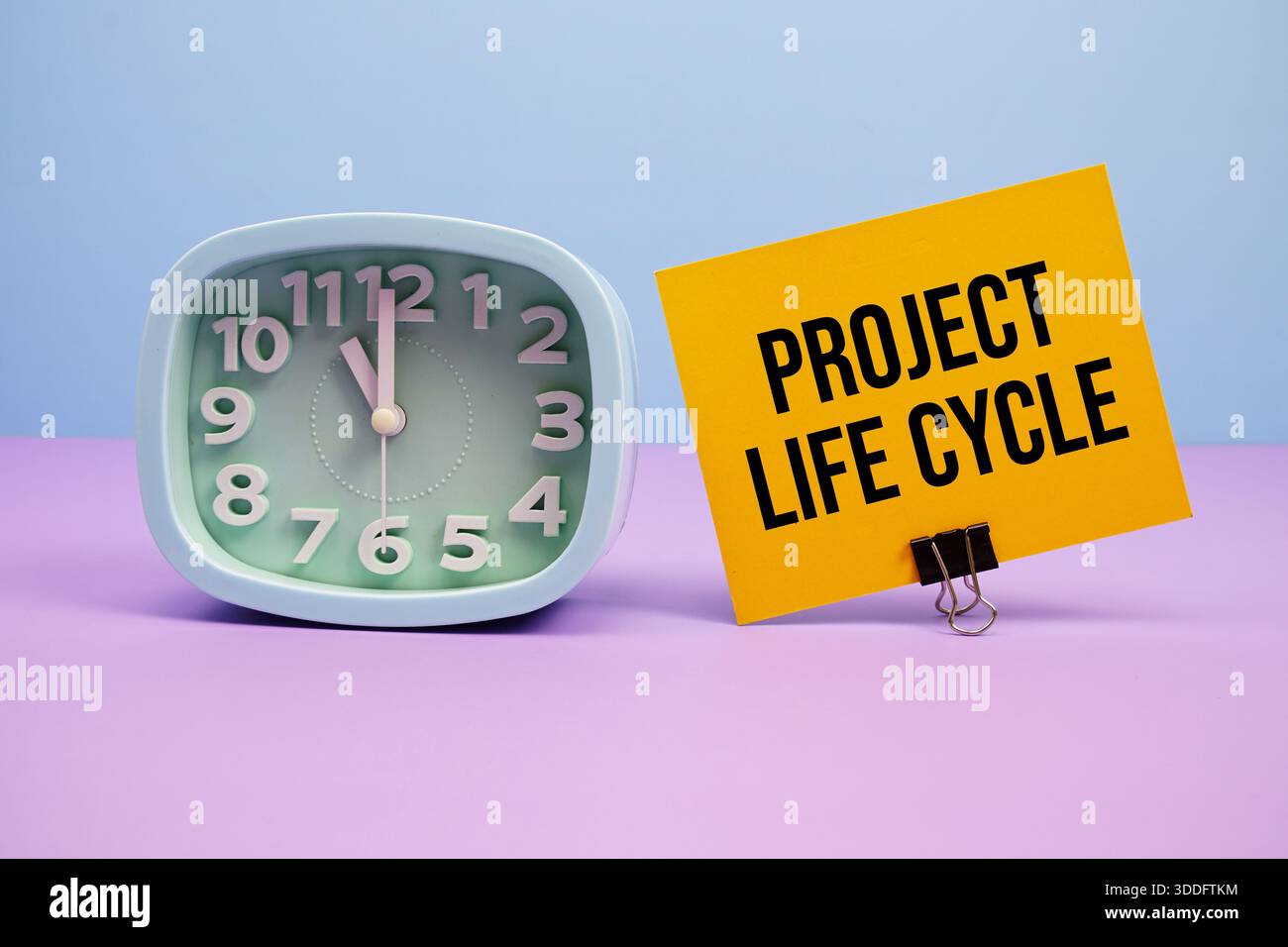 Text des Projektlebenszyklus und Wecker auf blauem und violettem Hintergrund Stockfoto