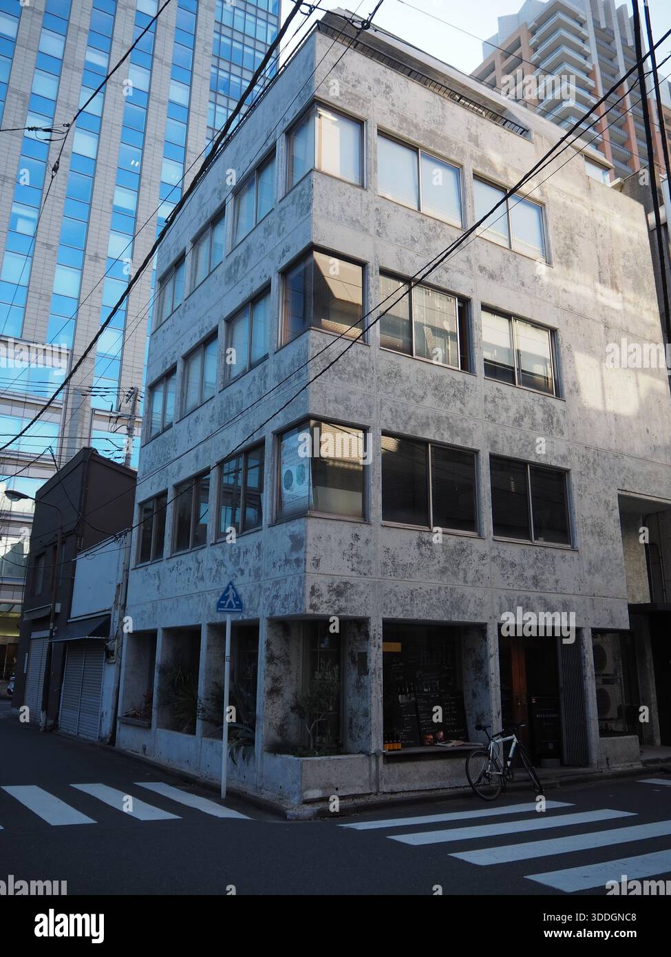 Eckgebäude in Jimbocho Tokio mit verwitterter Betonfassade und urbaner Geometrie bei ruhigem Tageslicht Stockfoto