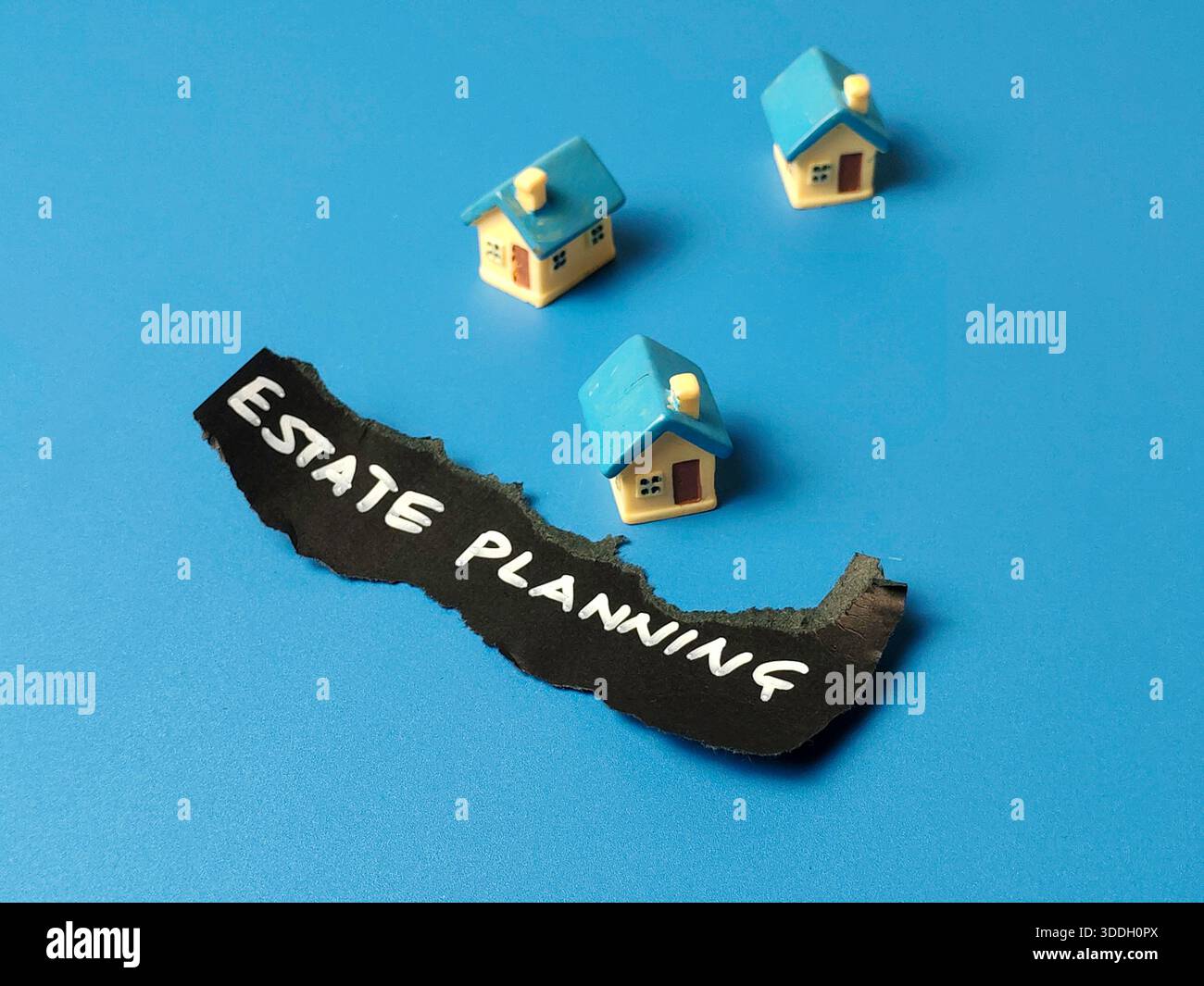 Immobilienplanungsschild mit kleinen Spielzeughäusern auf blauem Hintergrund für Immobilienrecht Erbrecht und Finanzvermögen Management Konzept Stockfoto