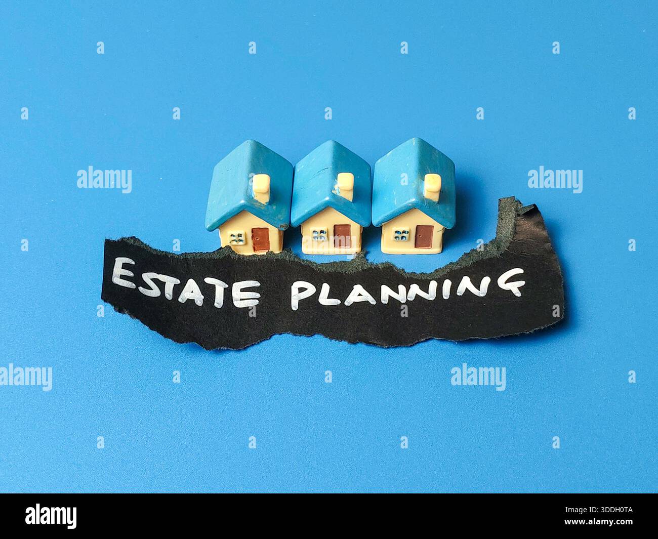 Immobilienplanungsschild mit kleinen Spielzeughäusern auf blauem Hintergrund für Immobilienrecht Erbrecht und Finanzvermögen Management Konzept Stockfoto