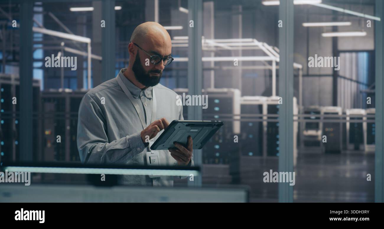 Koordination vor Ort, IT-Spezialist, der das Tablet zur Diagnose des Rack-Status verwendet. Fokussierter IT-Experte diagnostiziert den Server-Rack-Status mithilfe eines mobilen Tablet-Geräts. Koordination und Fehlerbehebung vor Ort. Stockfoto
