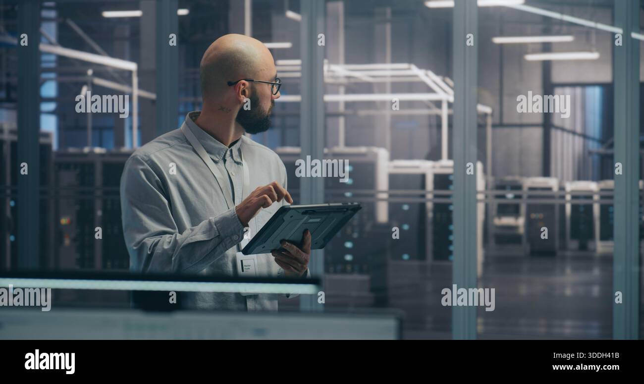 Koordination vor Ort, IT-Spezialist, der das Tablet zur Diagnose des Rack-Status verwendet. Fokussierter IT-Experte diagnostiziert den Server-Rack-Status mithilfe eines mobilen Tablet-Geräts. Koordination und Fehlerbehebung vor Ort. Stockfoto