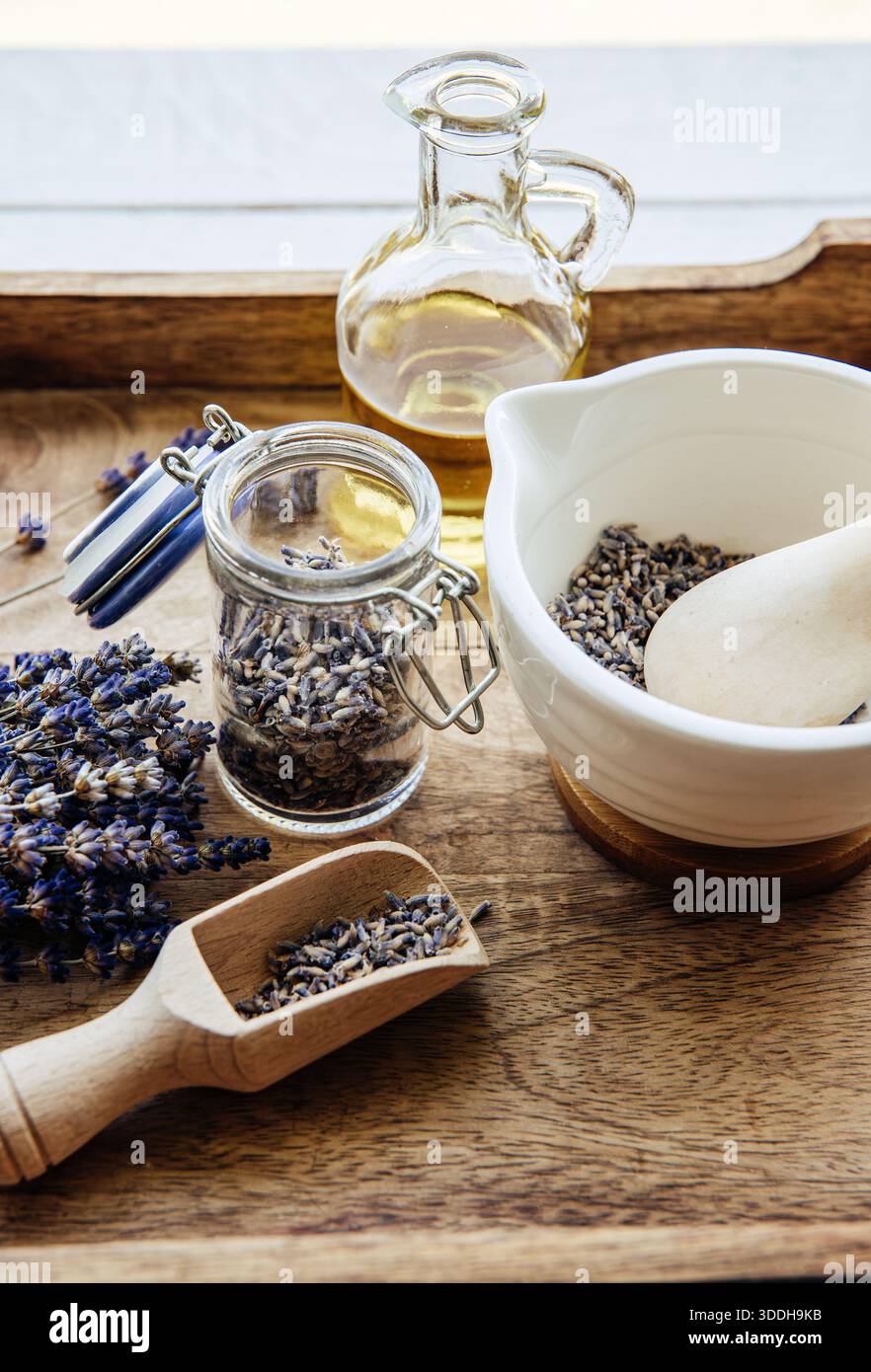 Herstellung von kaltem Lavendelöl. Olivenöl, getrocknete Lavendelblüten, Puds in einem Glas. Ein Mörser und Pissel, zusammen mit einem Bündel Lavendel. Stockfoto