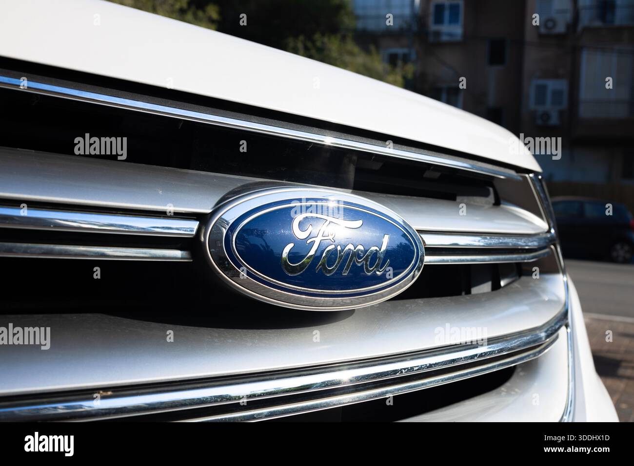 Nahaufnahme des blauen Ford-Emblems auf einem silbernen Kühlergrill eines weißen Autos, Givatayim, Israel, 4. Dezember 2025 Stockfoto