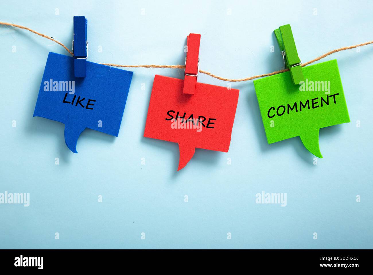 Sprache bläht sich mit Wörtern wie, Teilen, Kommentaren, die an einem Seil hängen, vor blauem Hintergrund Stockfoto