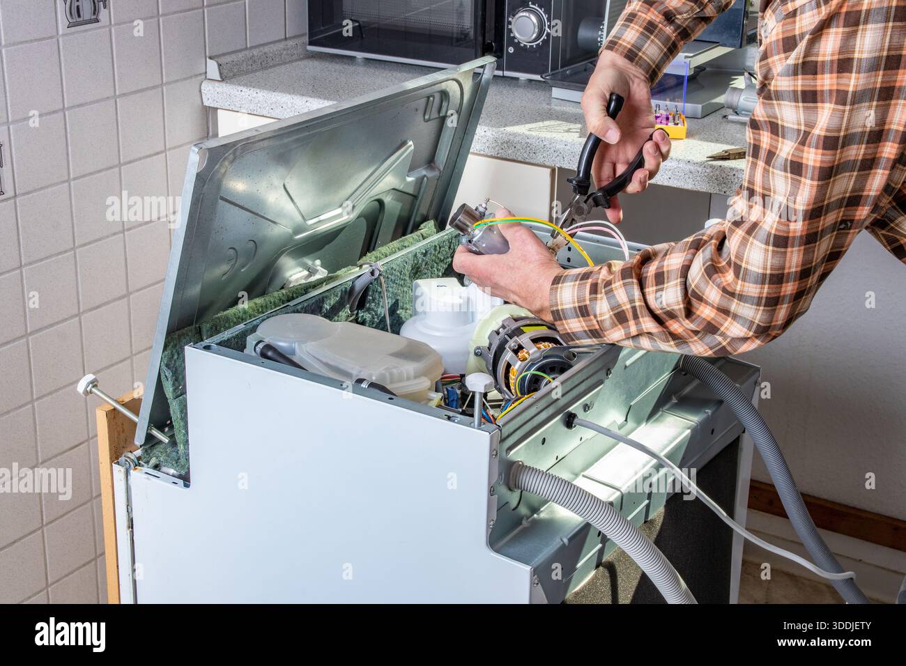 Leute, die sich für Techniker Jobs. Gerät nach der Reparatur oder Heimwerker arbeitet auf gebrochen Geschirrspüler in der Küche. Arbeiter ist Wechsel des Heizelementes. Stockfoto