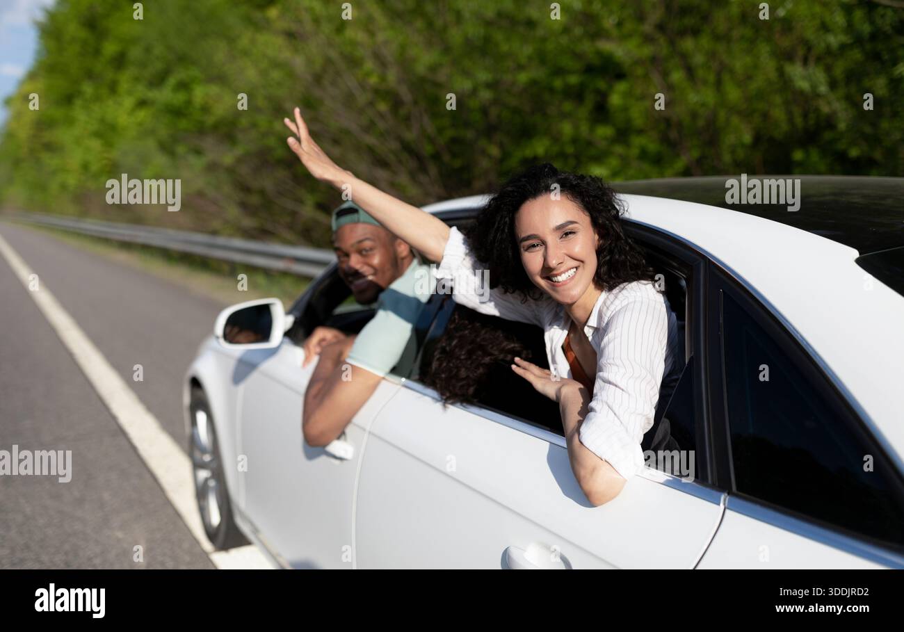 Die besten Freunde aus verschiedenen Rassen, die zusammen mit dem Auto reisen, durch Fenster schauen und im Sommer eine lustige Reise machen Stockfoto