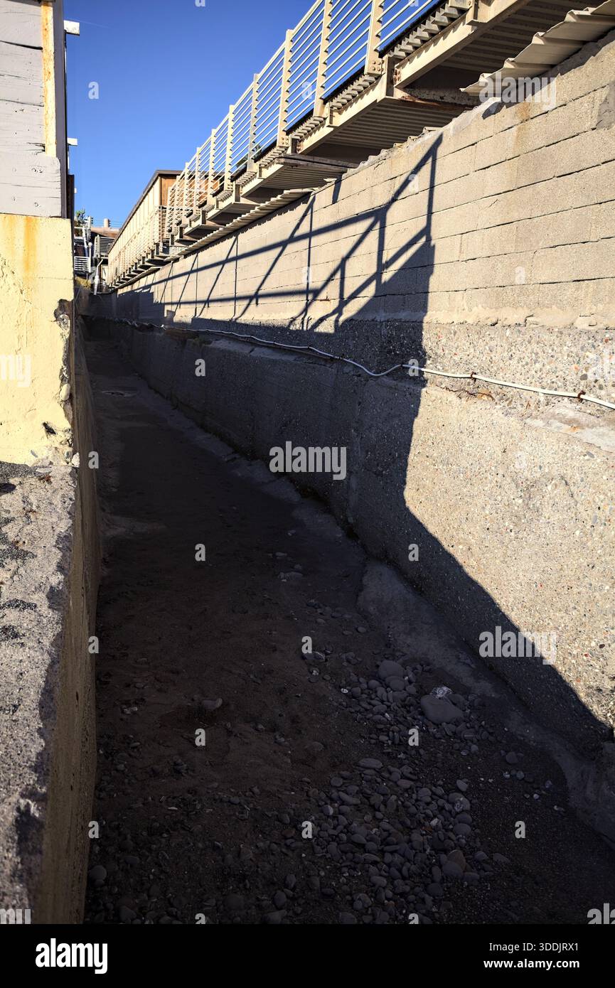 Trockener Betonkanal von unten gesehen, von der Sonne auf seiner Spitze beleuchtet Stockfoto
