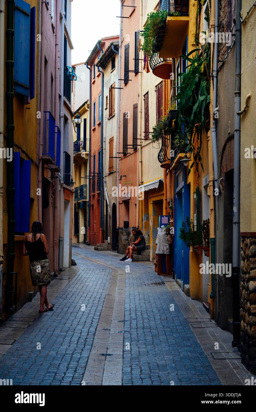 Frau sitzt auf einer Fensterbank in den Kopfsteinpflasterstraßen von Collioure, Cote Vermeille, Katalonien, Frankreich Stockfoto