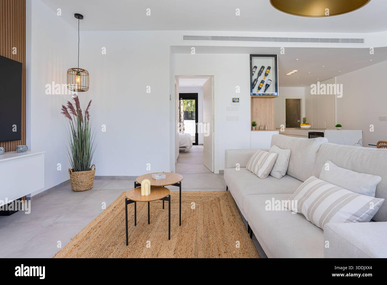 Der moderne Wohnbereich verfügt über ein helles Sofa, Holzakzente und neutrale Farbtöne mit natürlichen Texturen Stockfoto