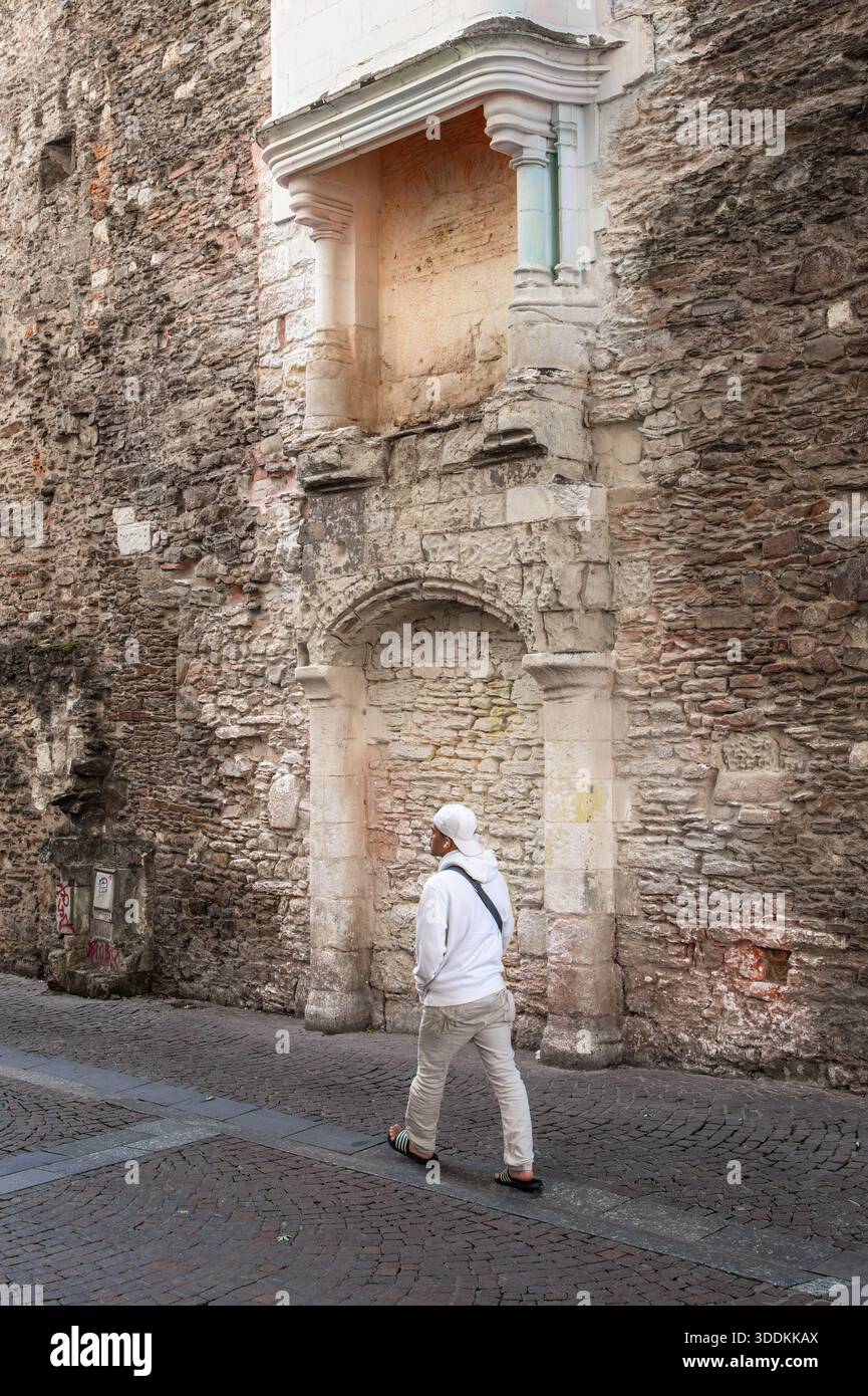 Nantes, Frankreich - 5. August 2025: Eine Person, die an einer alten Steinmauer mit einem kleinen Bogengang und dekorativen Elementen vorbeiläuft, die historische Archi zeigen Stockfoto