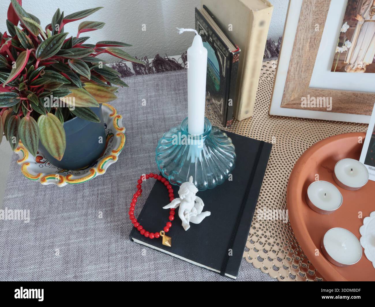 Katholische Gläubige Ecke zu Hause. Symbole und Kerzen. Engel Figur und Armband. Glaube, Symbole und Traditionen. Stockfoto