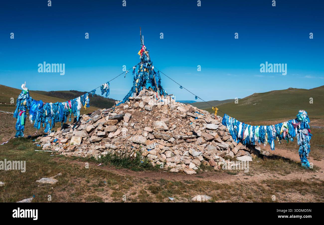 Mongolischer Ovoo mit blauen Gebetsfahnen unter klarem Himmel Stockfoto