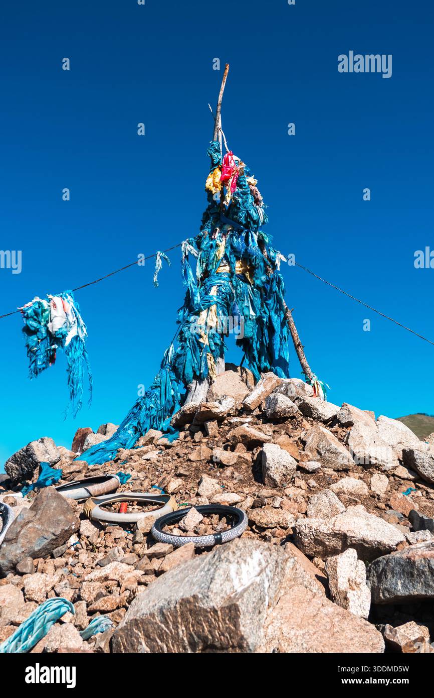 Mongolischer Ovoo mit blauen Gebetsfahnen unter klarem Himmel Stockfoto