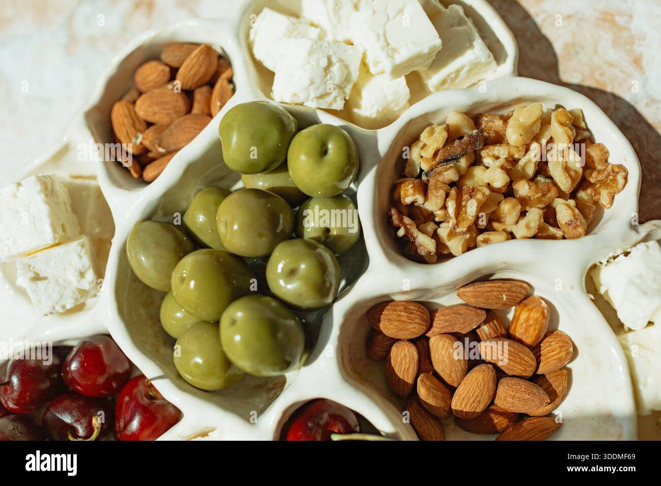 Mediterrane Vorspeisenplatte mit Feta, Oliven, Nüssen, Kirschen Stockfoto