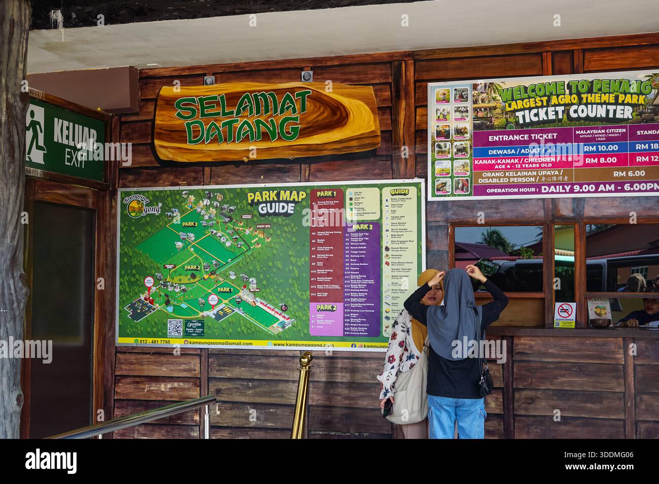 Penang, Malaysia, 5. Dezember 2025: Besucher am Ticketschalter von kg Agong, Penangs größtem Agro-Freizeitpark, mit Beschilderung und Preistafel. Stockfoto
